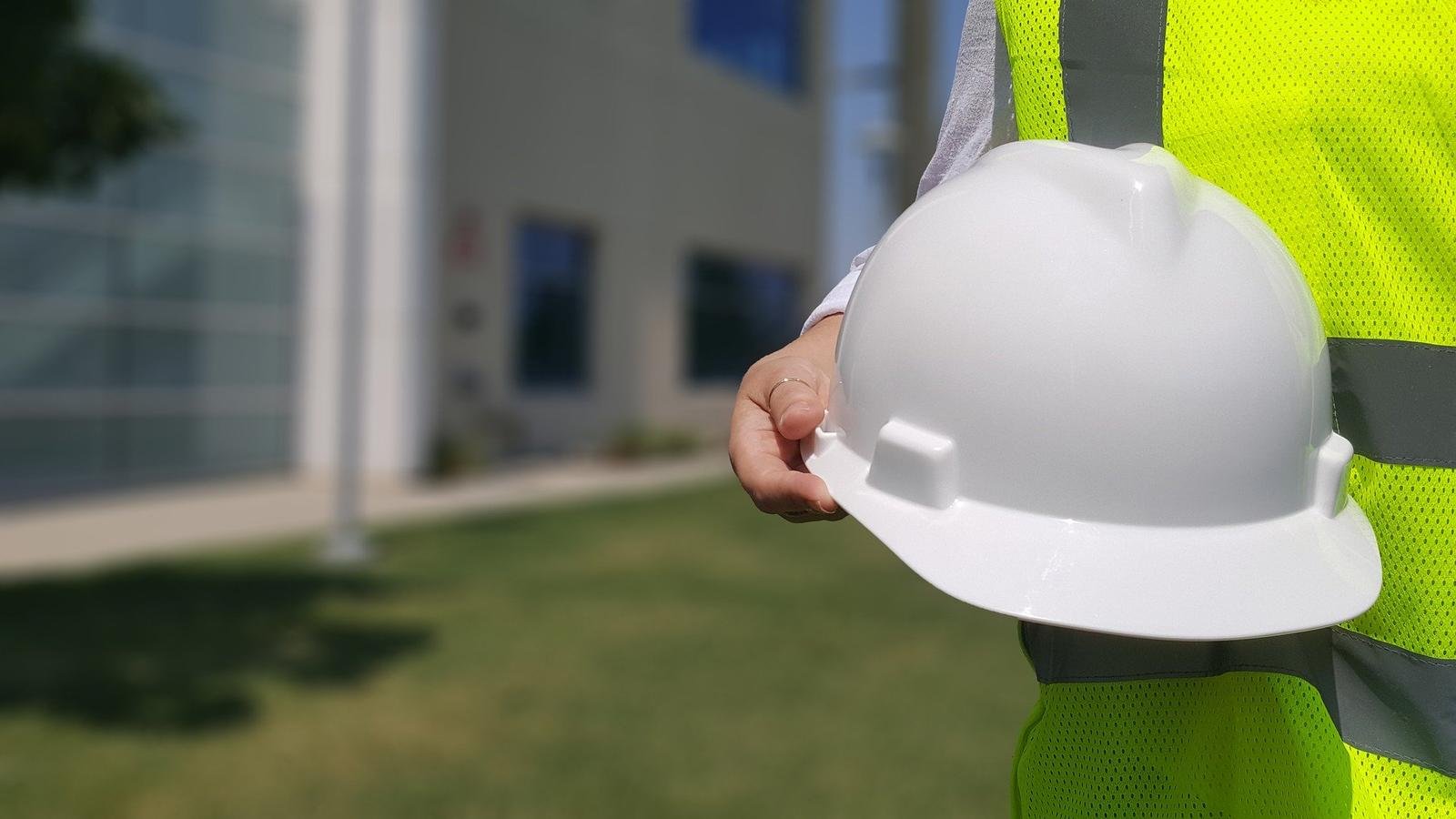 Profissional de segurança do trabalho em campo, com colete de alta visibilidade e capacete